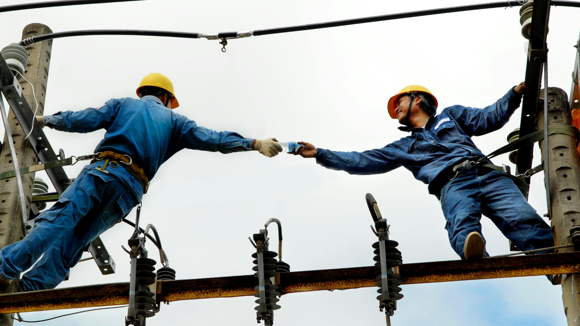 Workers handing off a tool on a steel beam